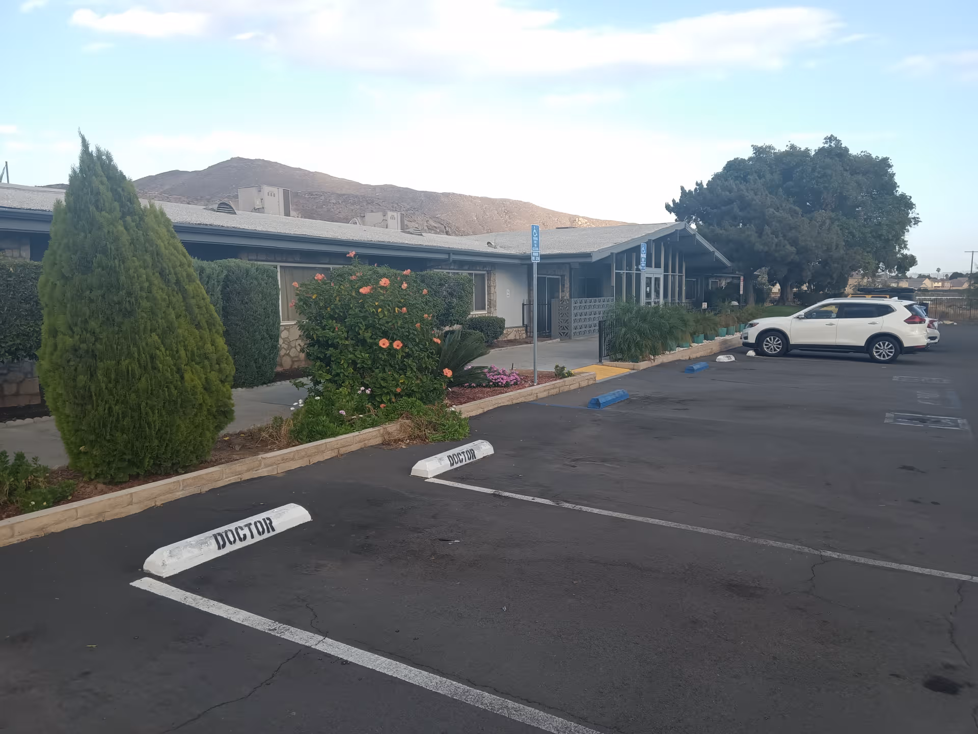 Exterior view of a single-story senior living facility with a landscaped parking lot.