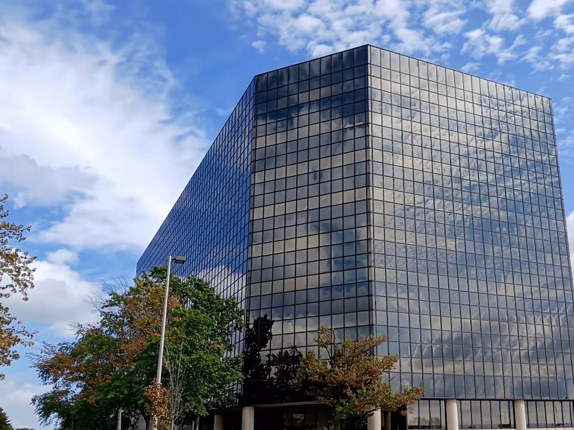 A tall glass building with reflective windows and a blue sky above.