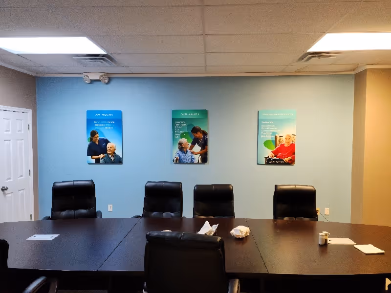 A conference room with a long dark table, black chairs, and posters on blue walls.