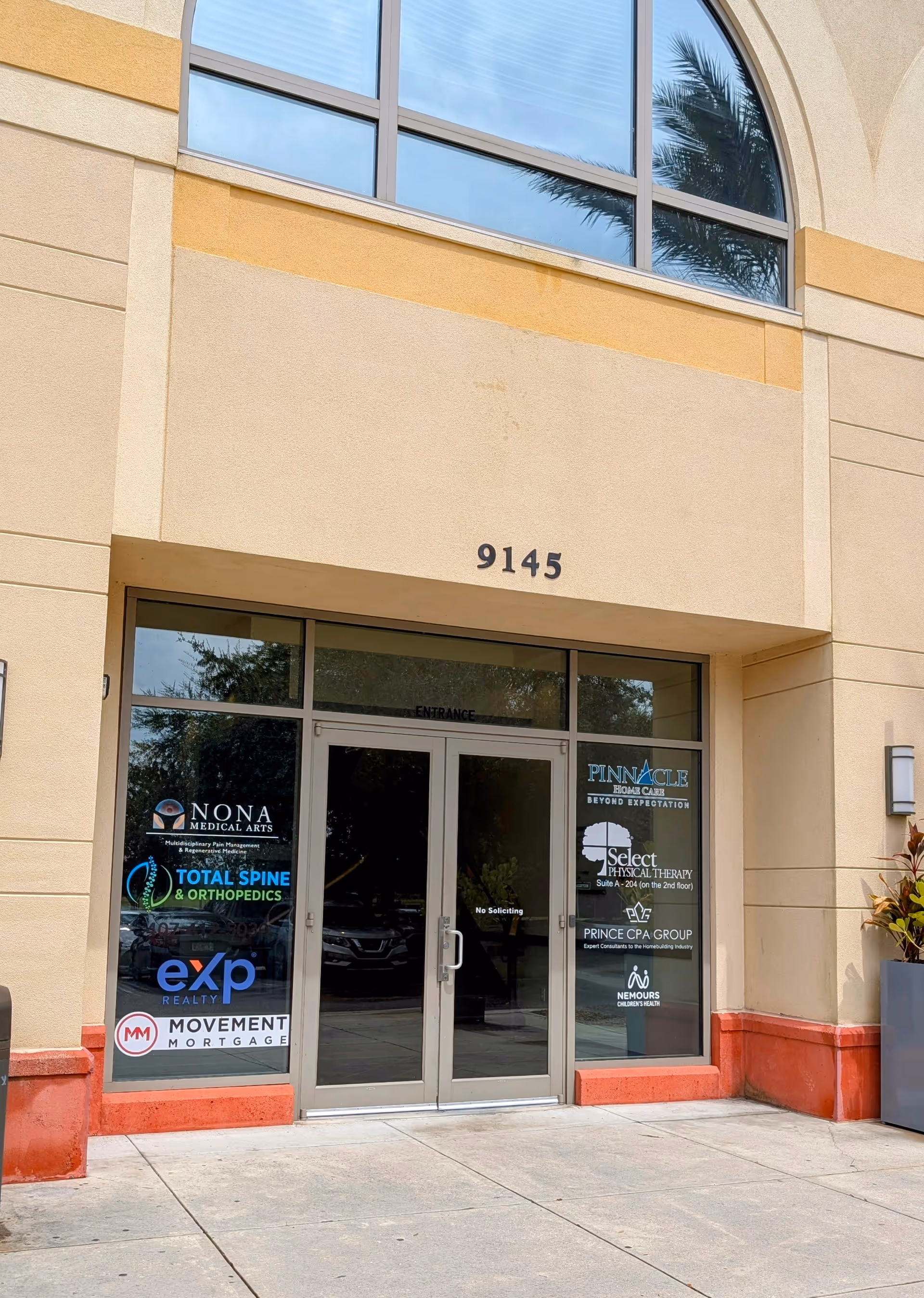 Beige building entrance with glass doors, marked 9145, and visible business signage.