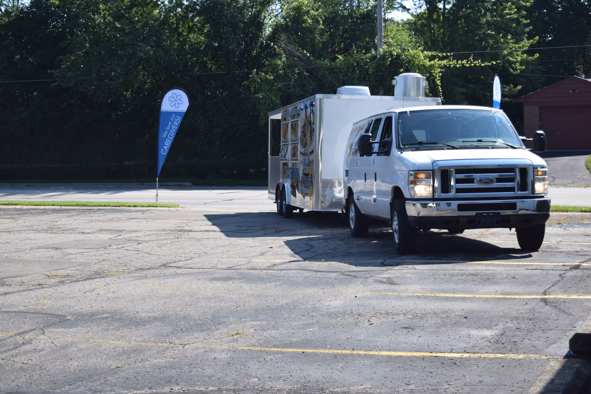 A white service truck with an attached trailer is parked in a large empty lot.