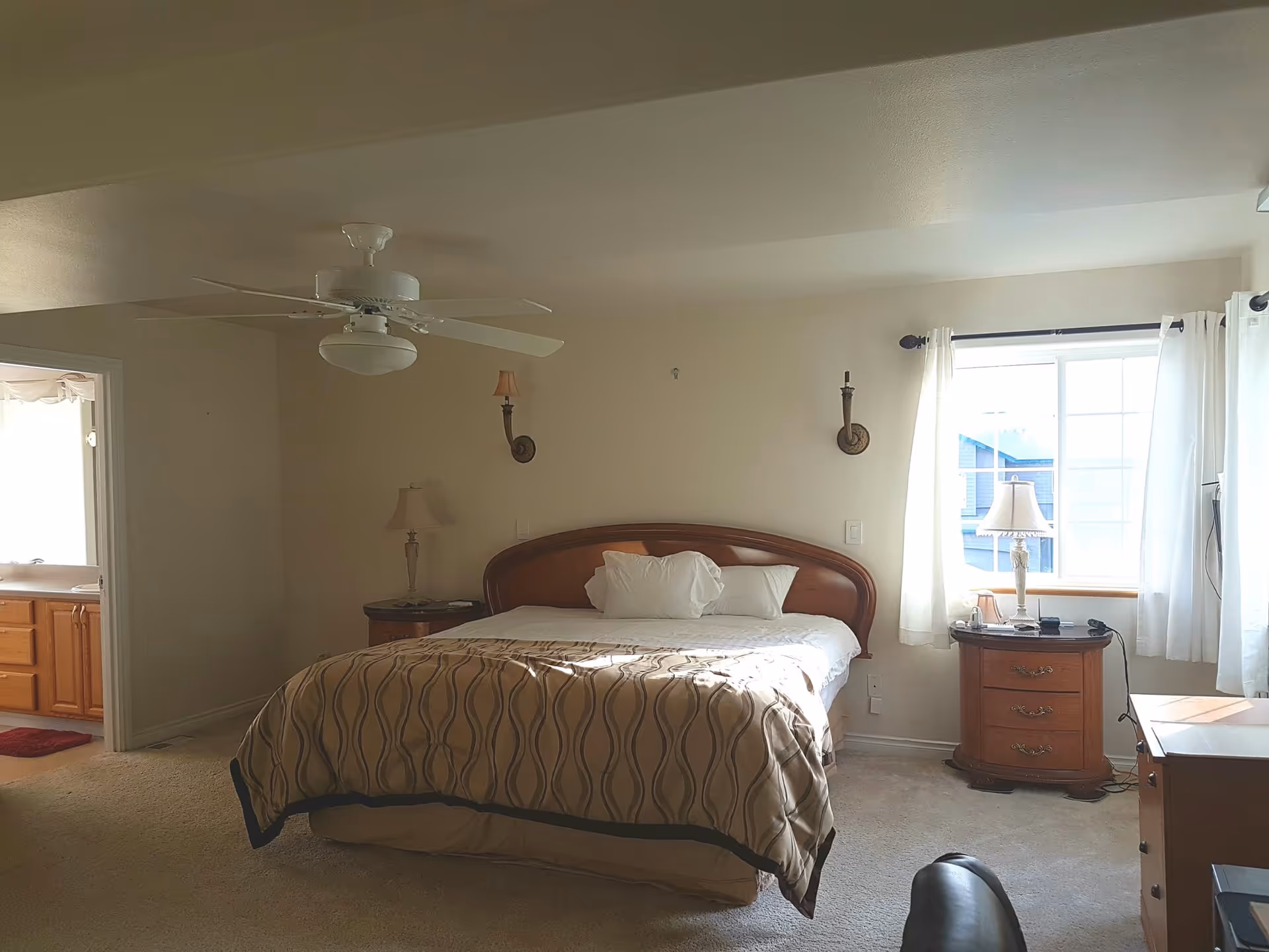 Bedroom with a large bed, two nightstands, lamps, a ceiling fan, and a window.