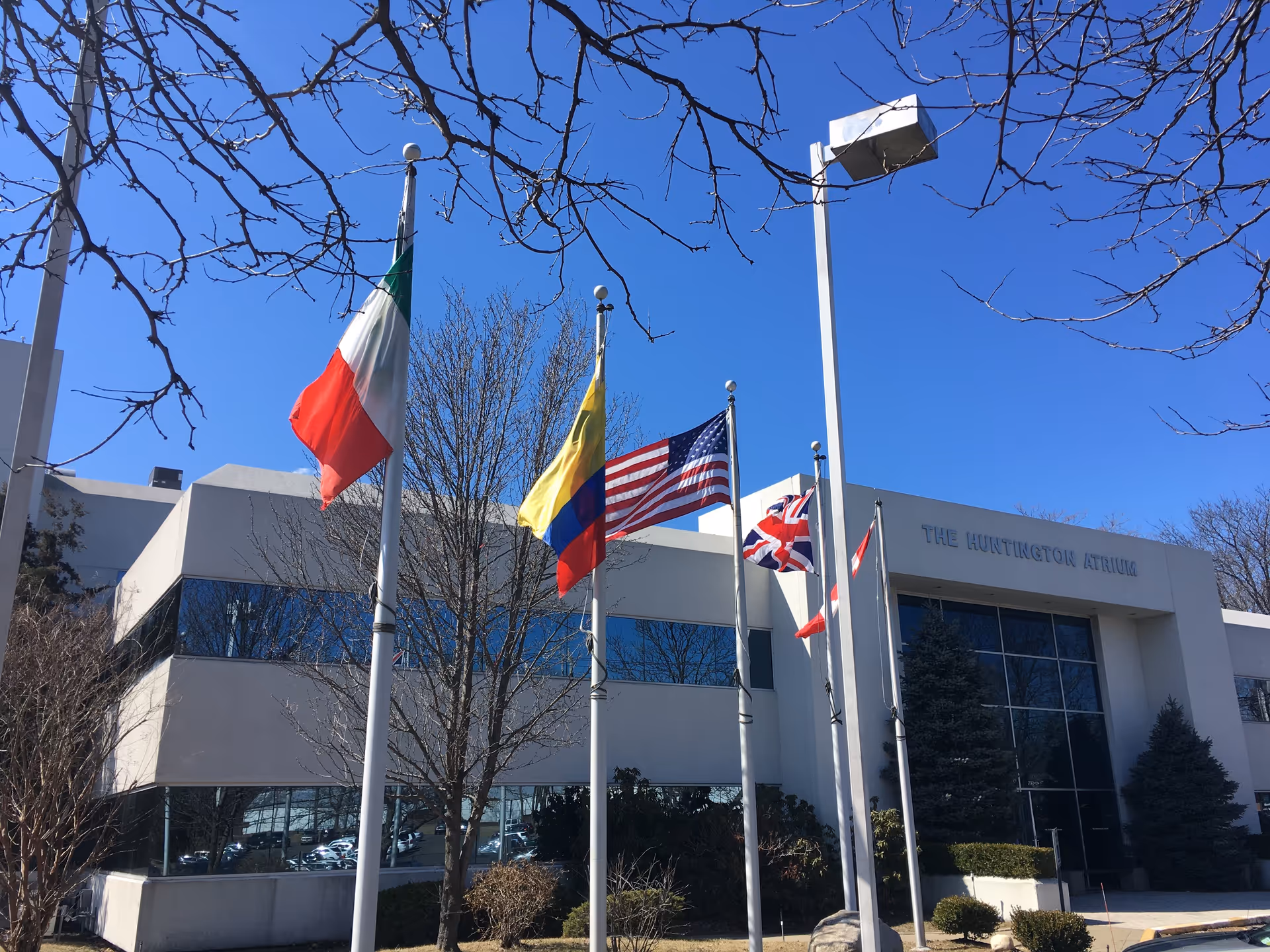 Front facade of a modern building with flagpoles and international flags