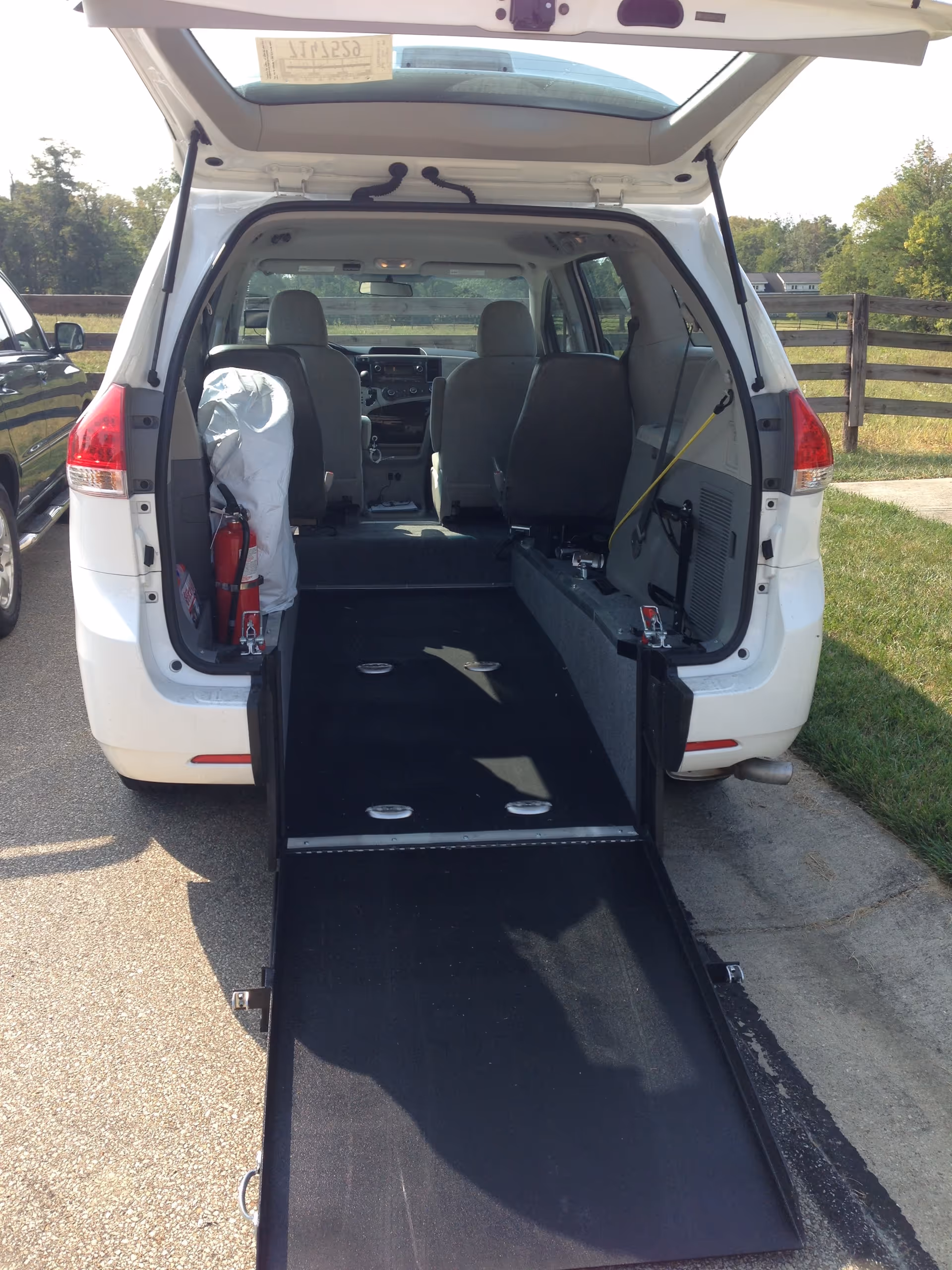 White van with lowered ramp, interior seats visible, ready for wheelchair transport.