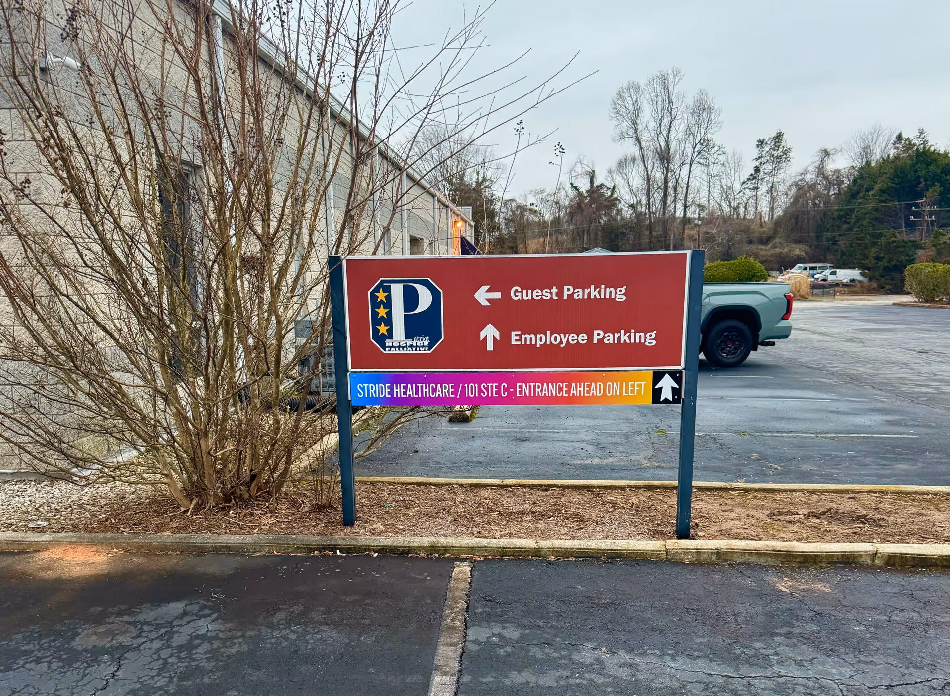 Red exterior sign showing guest and employee parking directions at Stride HealthCare.