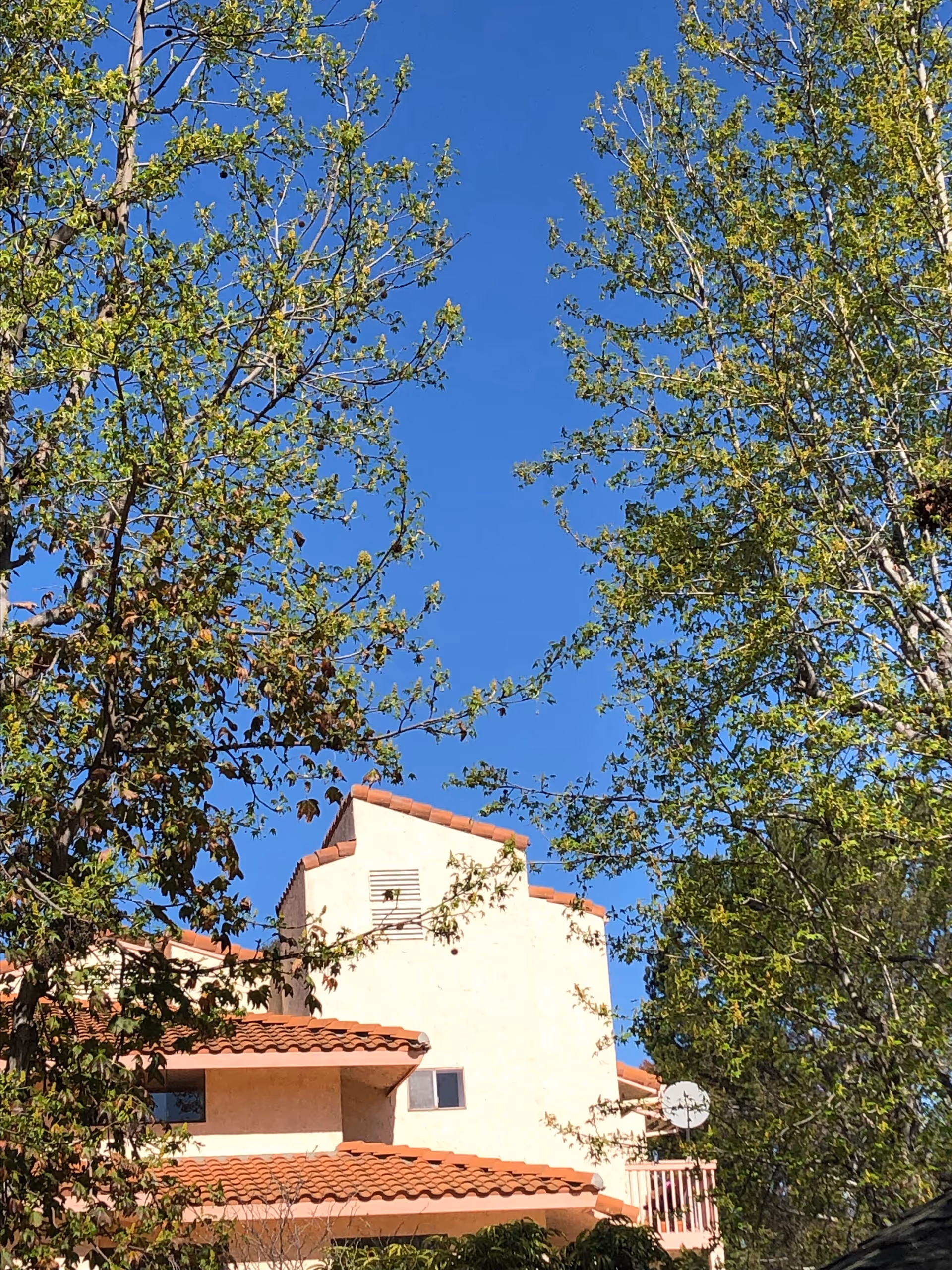 Exterior view of Woodbridge Manor senior living facility with tan stucco walls and red-tiled roof.