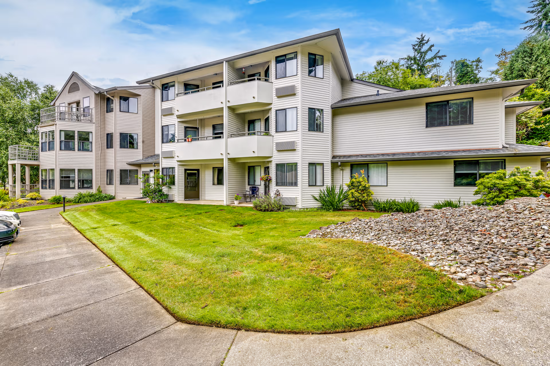 Three-story Solstice Senior Living building with balconies, green lawn, and curved driveway.