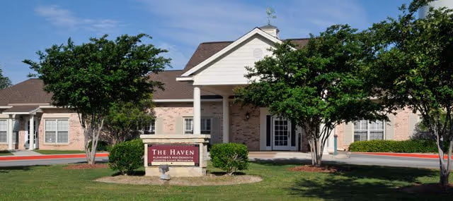 Front view of The Haven in the Summit senior living facility with a sign and trees.