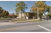 A beige Riverwood Center building sits on a corner street with trees.