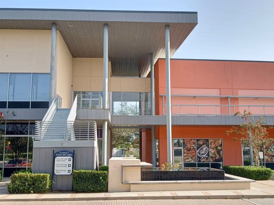 Modern building exterior with a covered entrance, stairs, and glass windows.