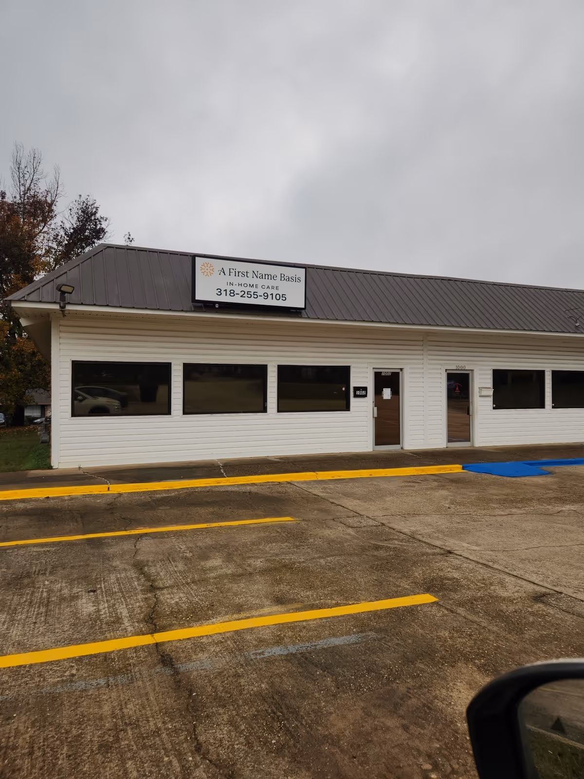 White, single-story building with sign reading A First Name Basis In-Home Care in a parking lot.