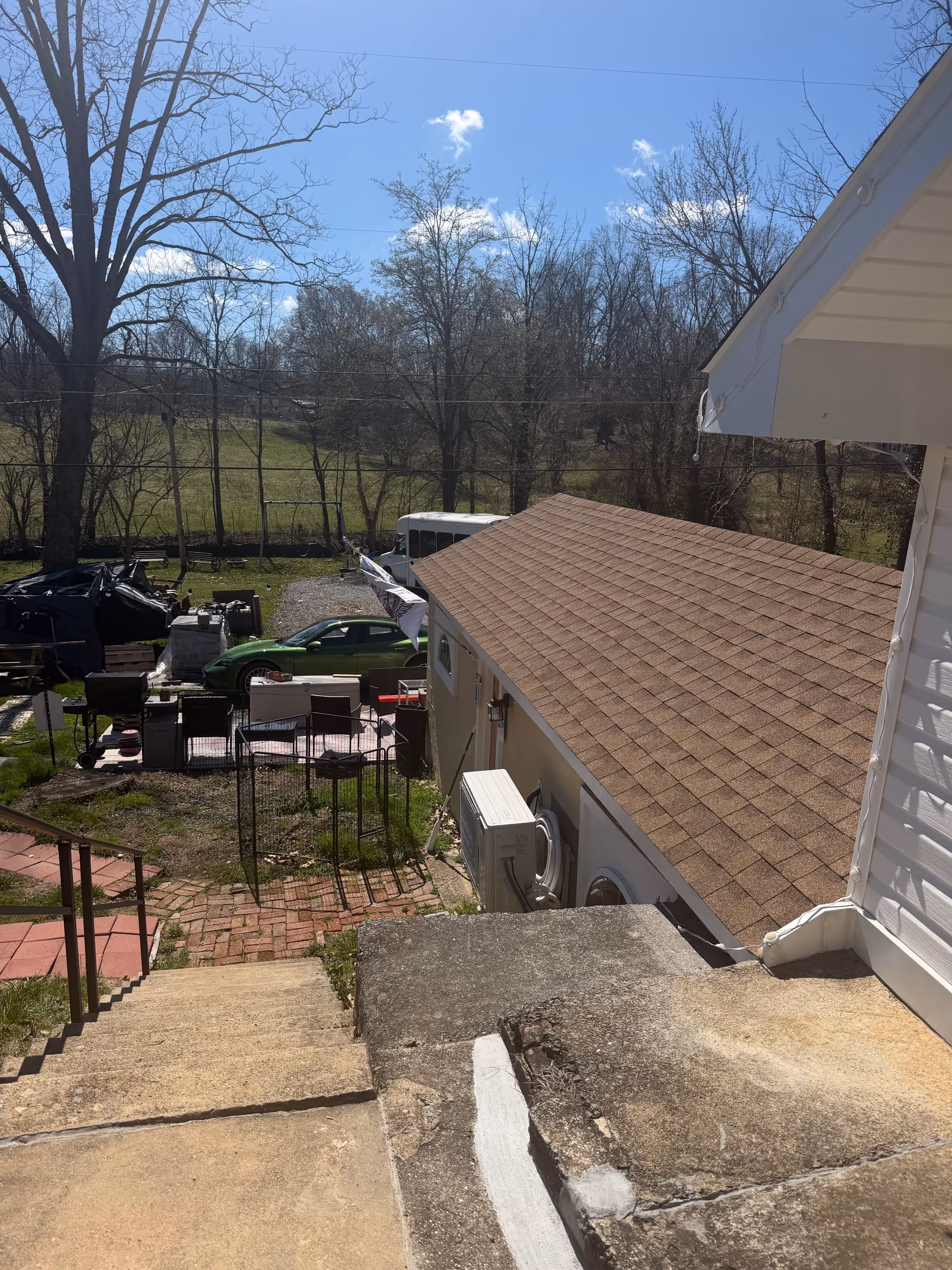 Backyard scene with steps, lawn chairs, and scattered belongings near a house.