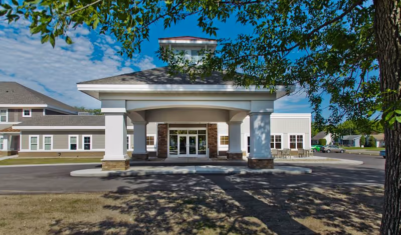Exterior view of a senior living facility entrance with a covered drop off area.