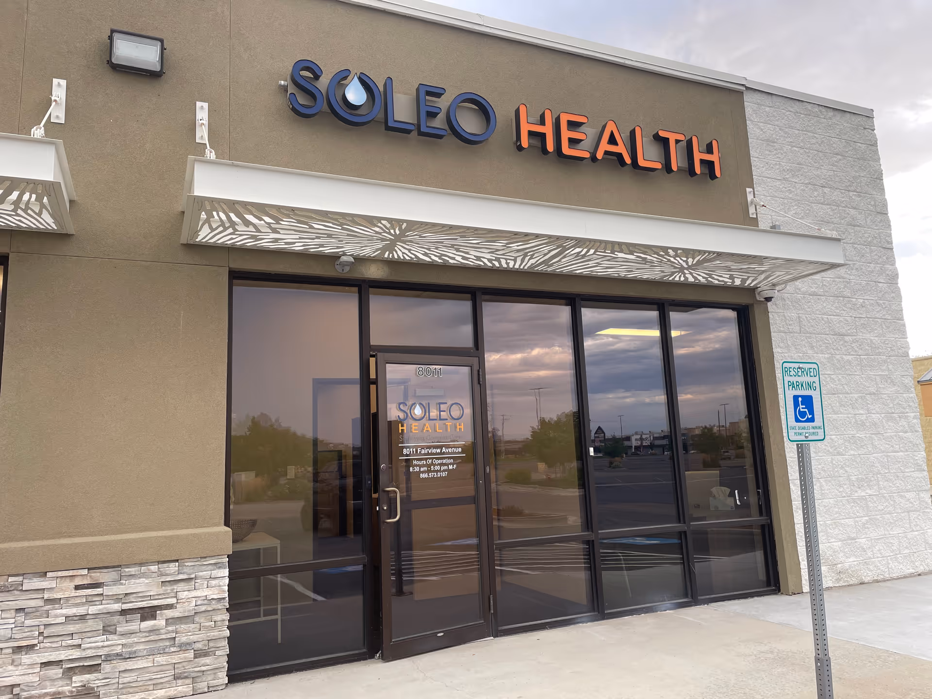 Exterior view of Soleo Health building with glass entrance and handicapped parking sign.
