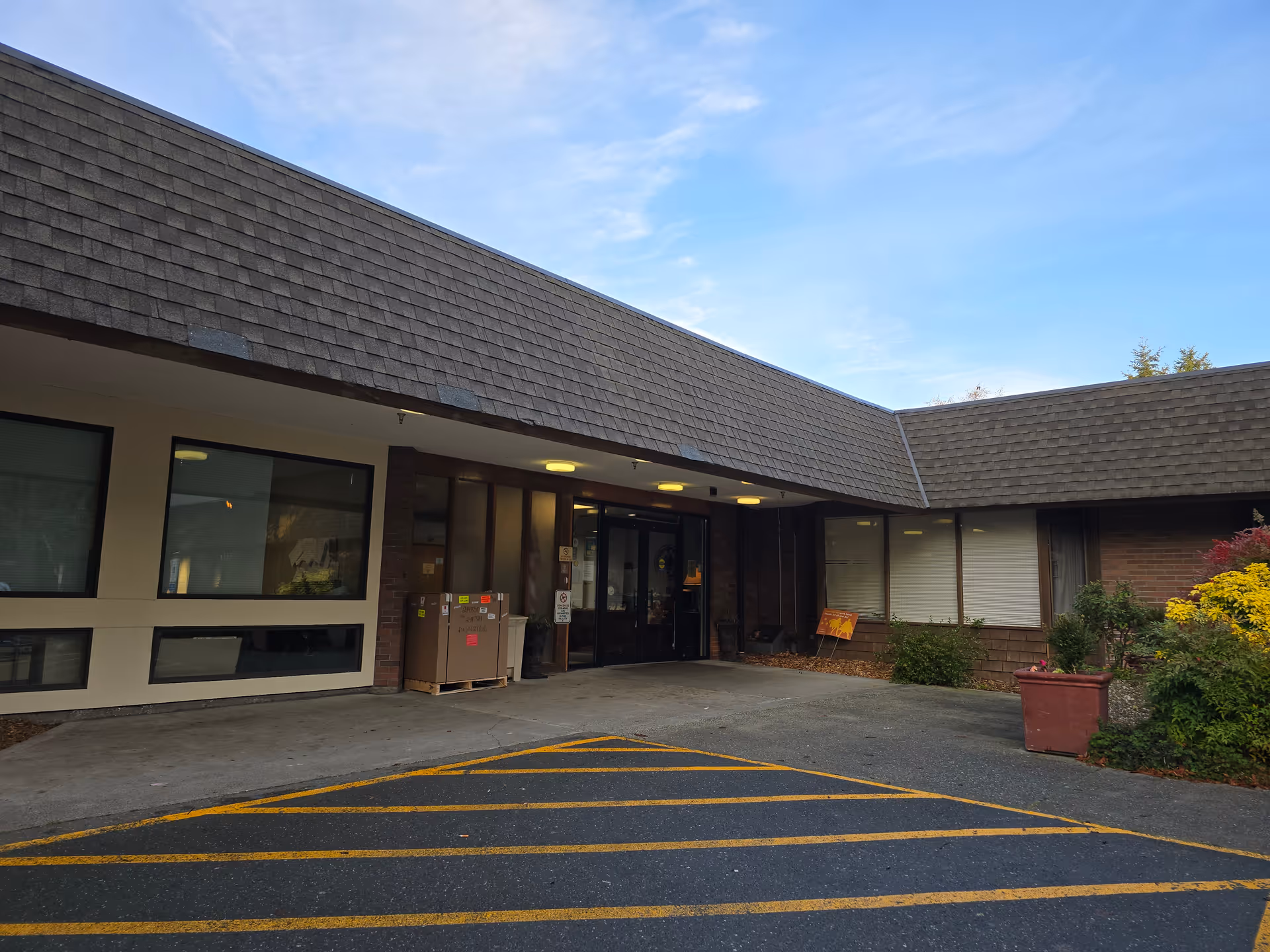 Exterior view of Ballard Center entrance with parking lot and plants.
