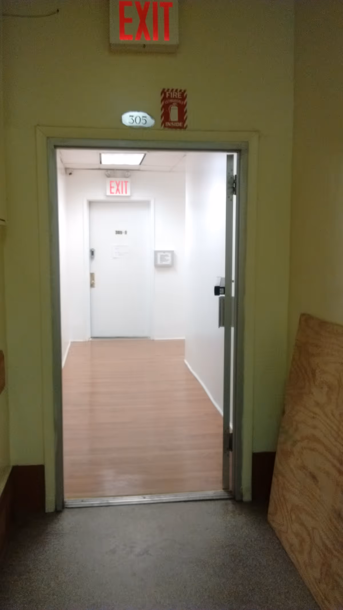 Interior hallway with an open doorway into a lit corridor and exit sign.