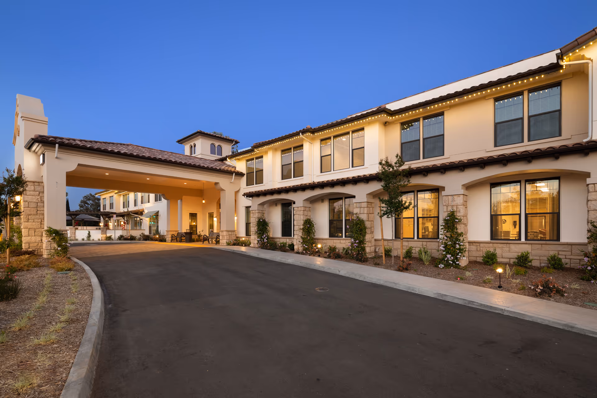 Two-story senior living facility exterior with a covered entrance and landscaped front.
