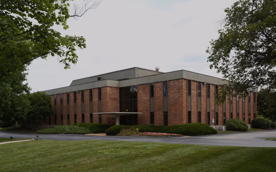 Brick senior living facility exterior with landscaping and a driveway.