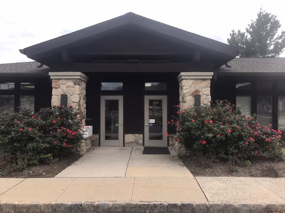 Senior living facility entrance with stone columns and blooming rose bushes