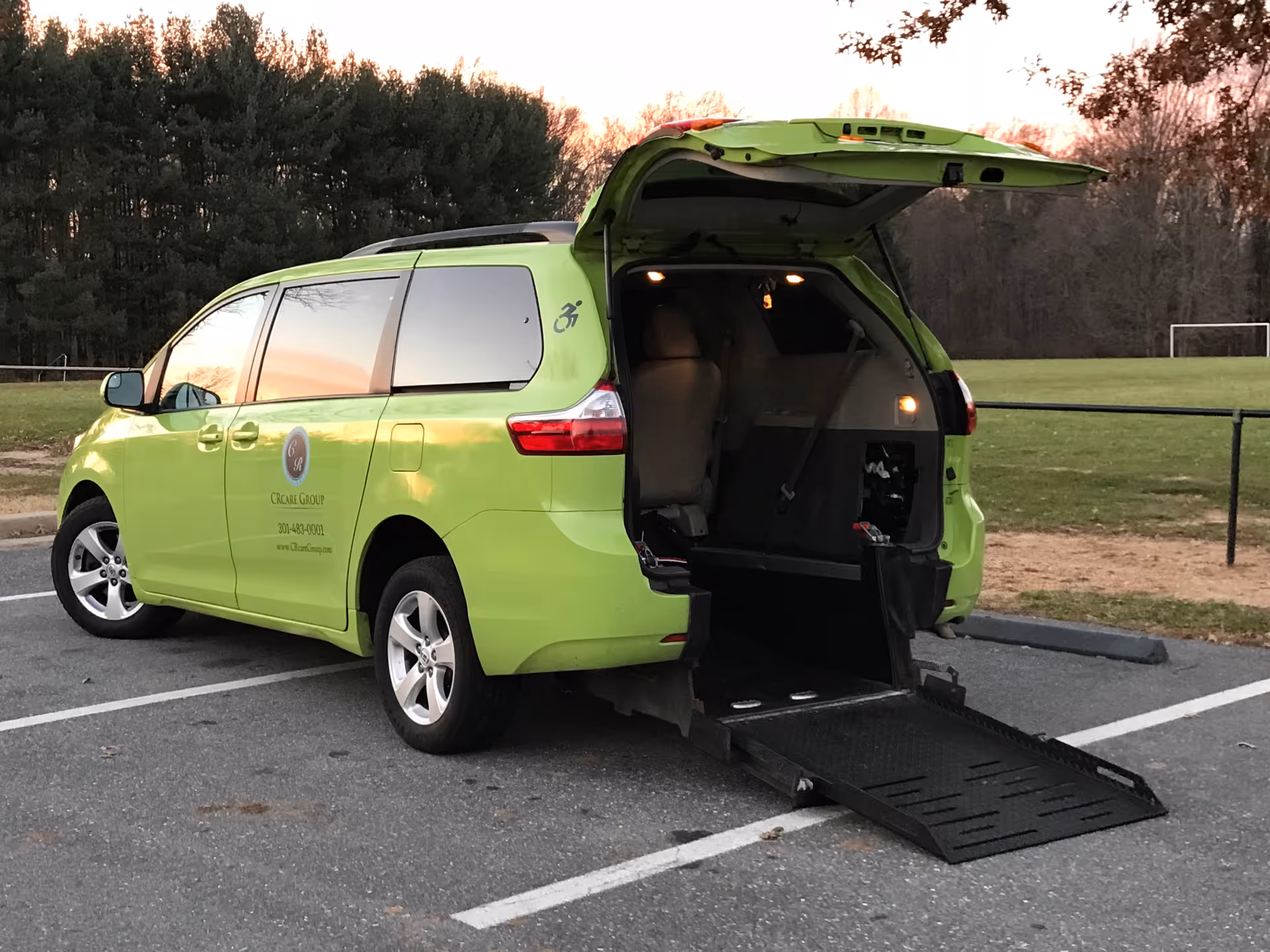 Bright green mobility van with wheelchair ramp deployed in a parking lot.