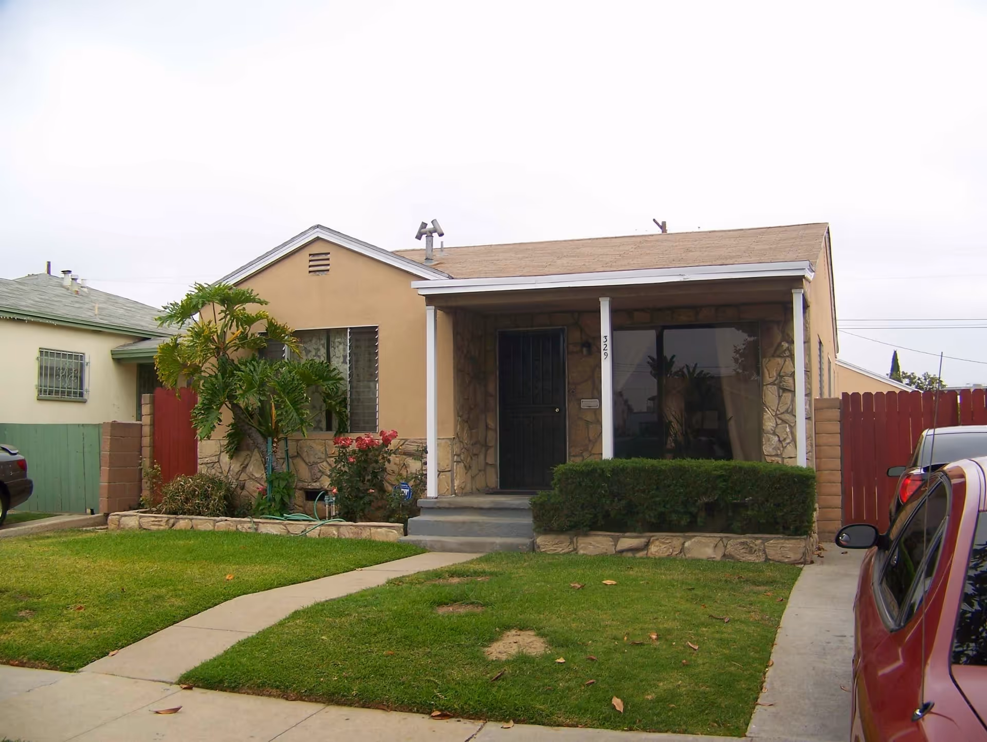 Single-story beige house with stone facade, small front porch, and a manicured lawn.