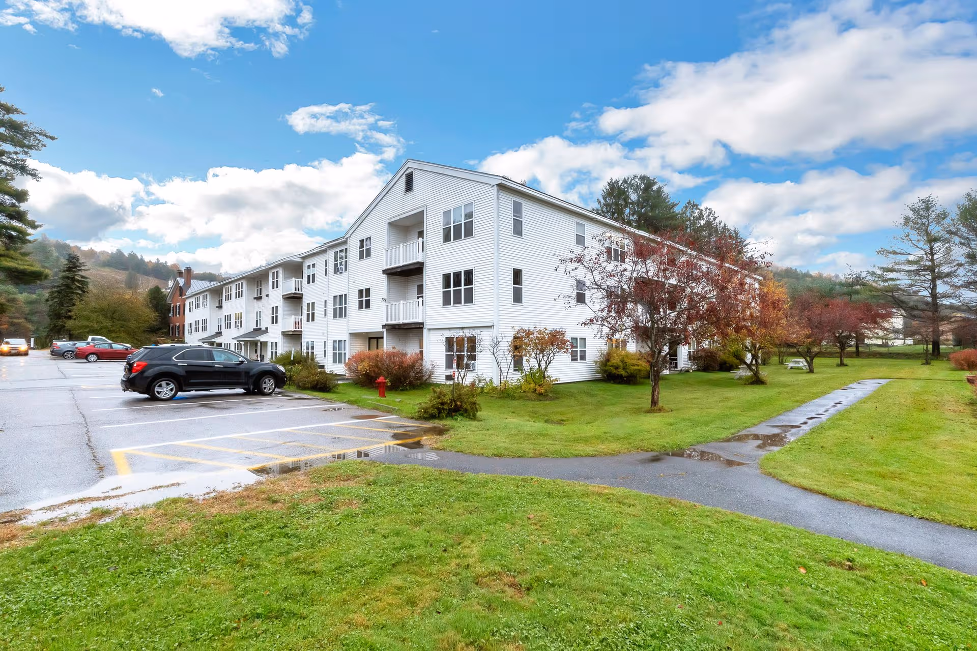 White, multi-story Williamstown Gardens Senior Living building with parking lot and well-kept green lawn.