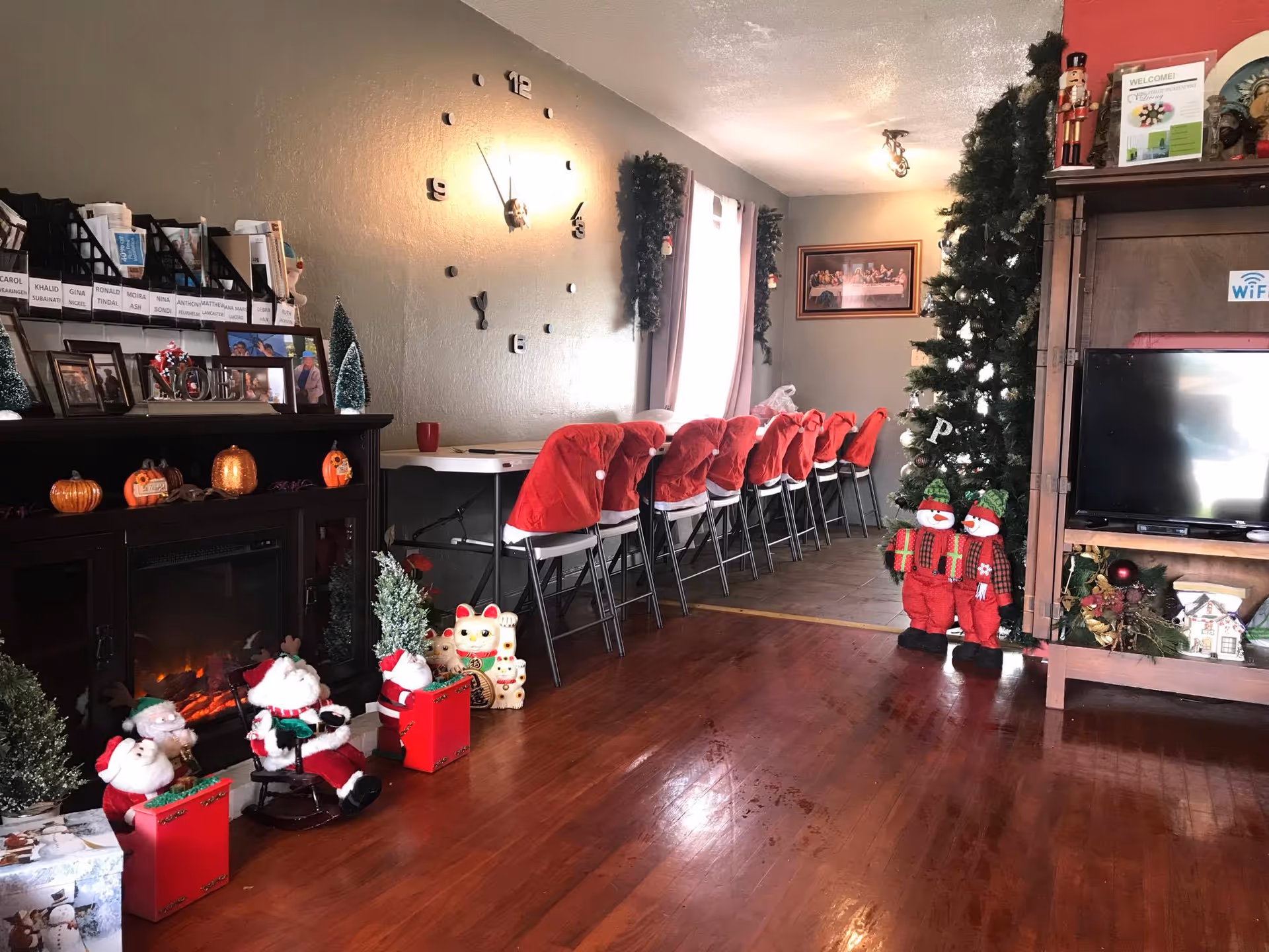 Festive senior living common room with red chairs lining a long table, Christmas tree, and decorations.