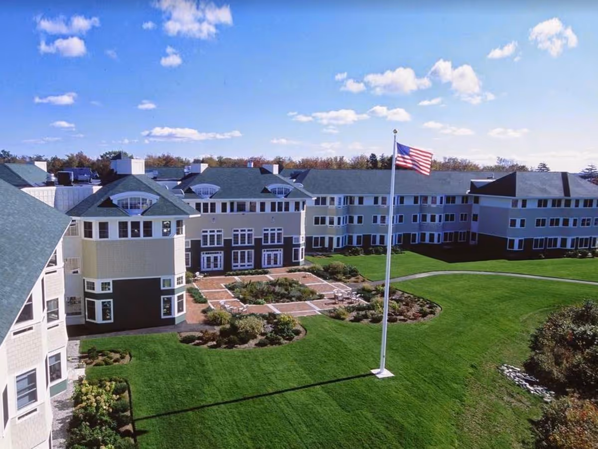 Aerial view of Piper Shores senior living campus with green lawns and a tall American flag.