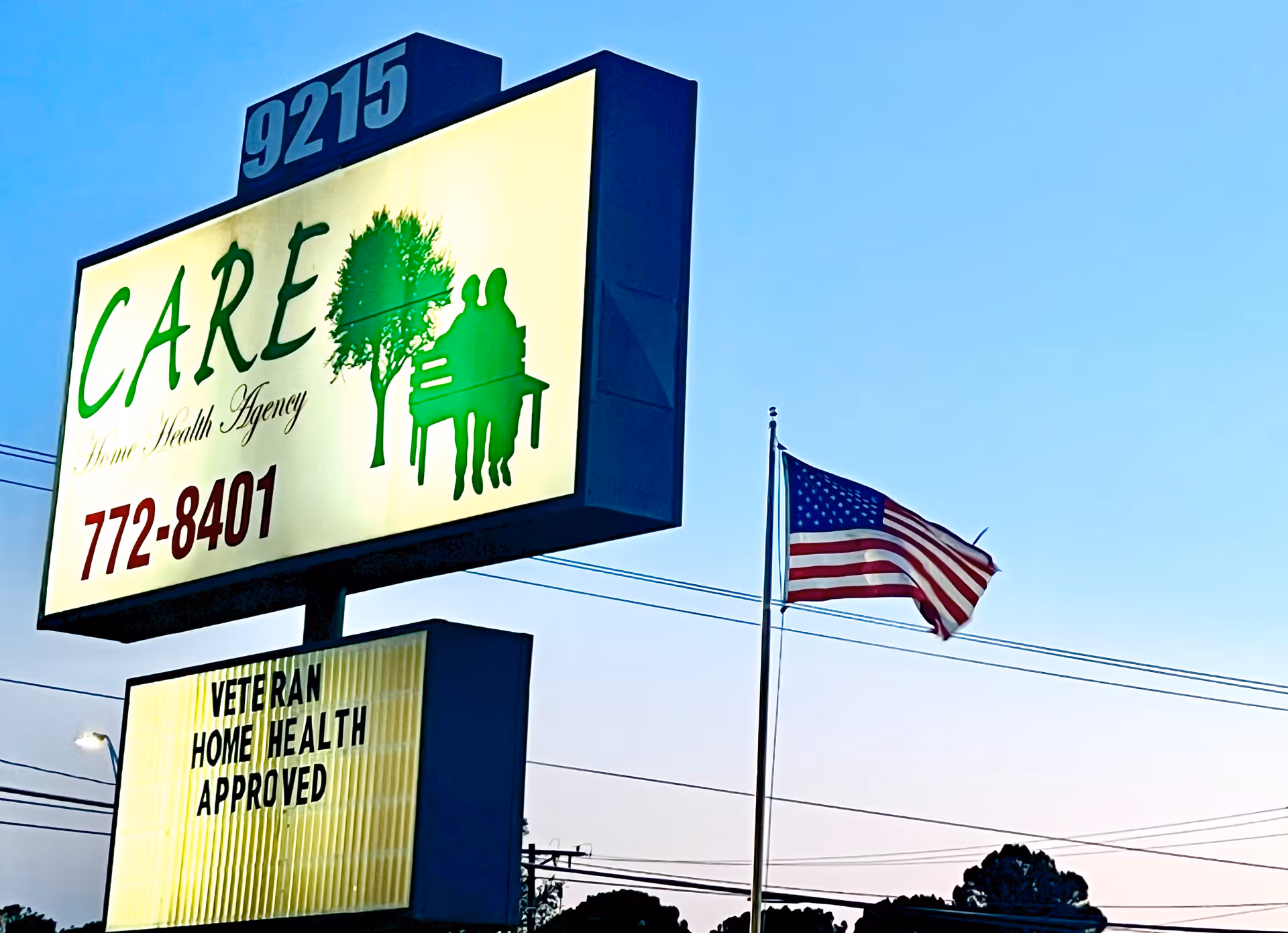 Outdoor sign for CARE Home Health Agency featuring a tree silhouette and a waving American flag.