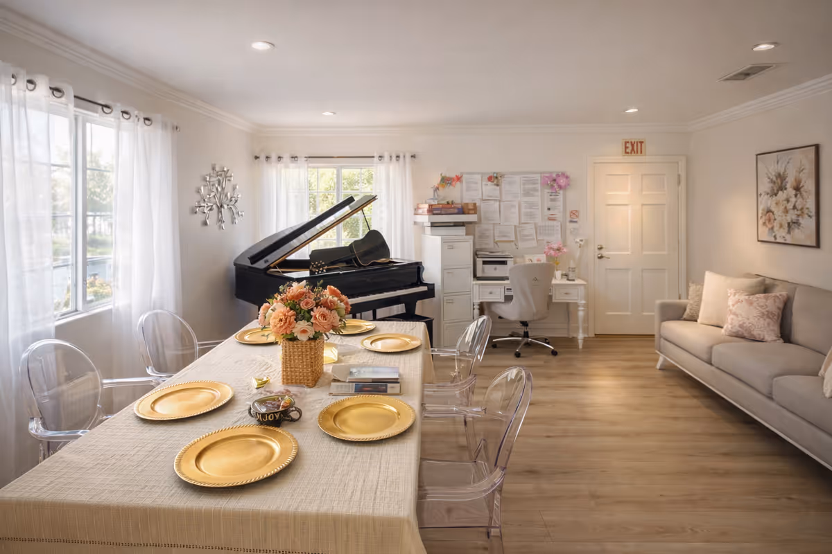 Bright living room with grand piano, long table set with gold plates and flowers.