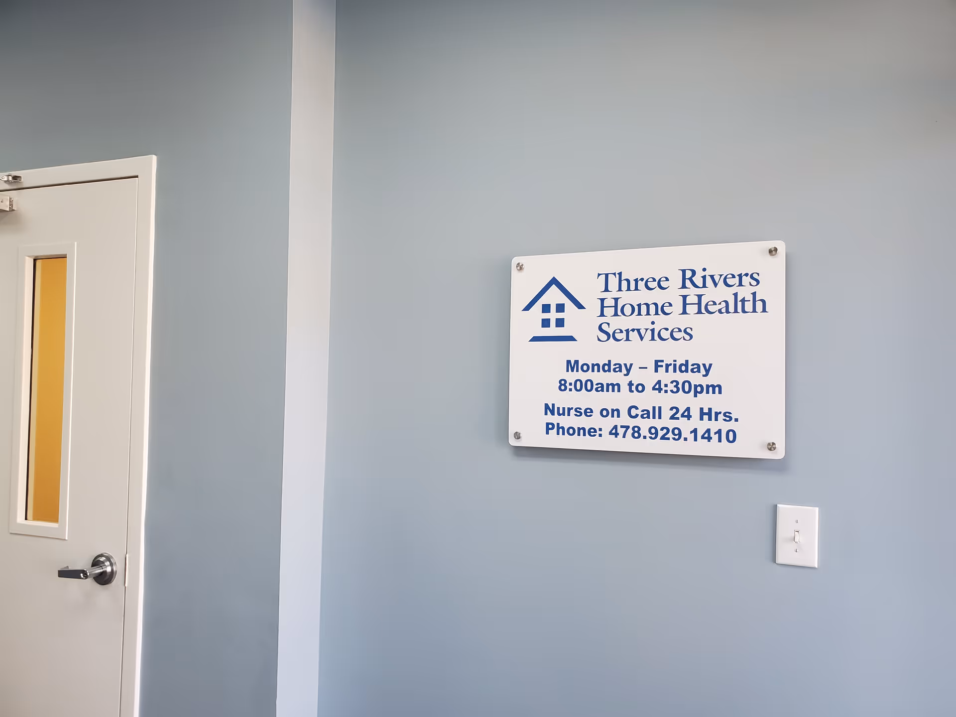 Interior wall with a Three Rivers Home Health Services sign beside a door