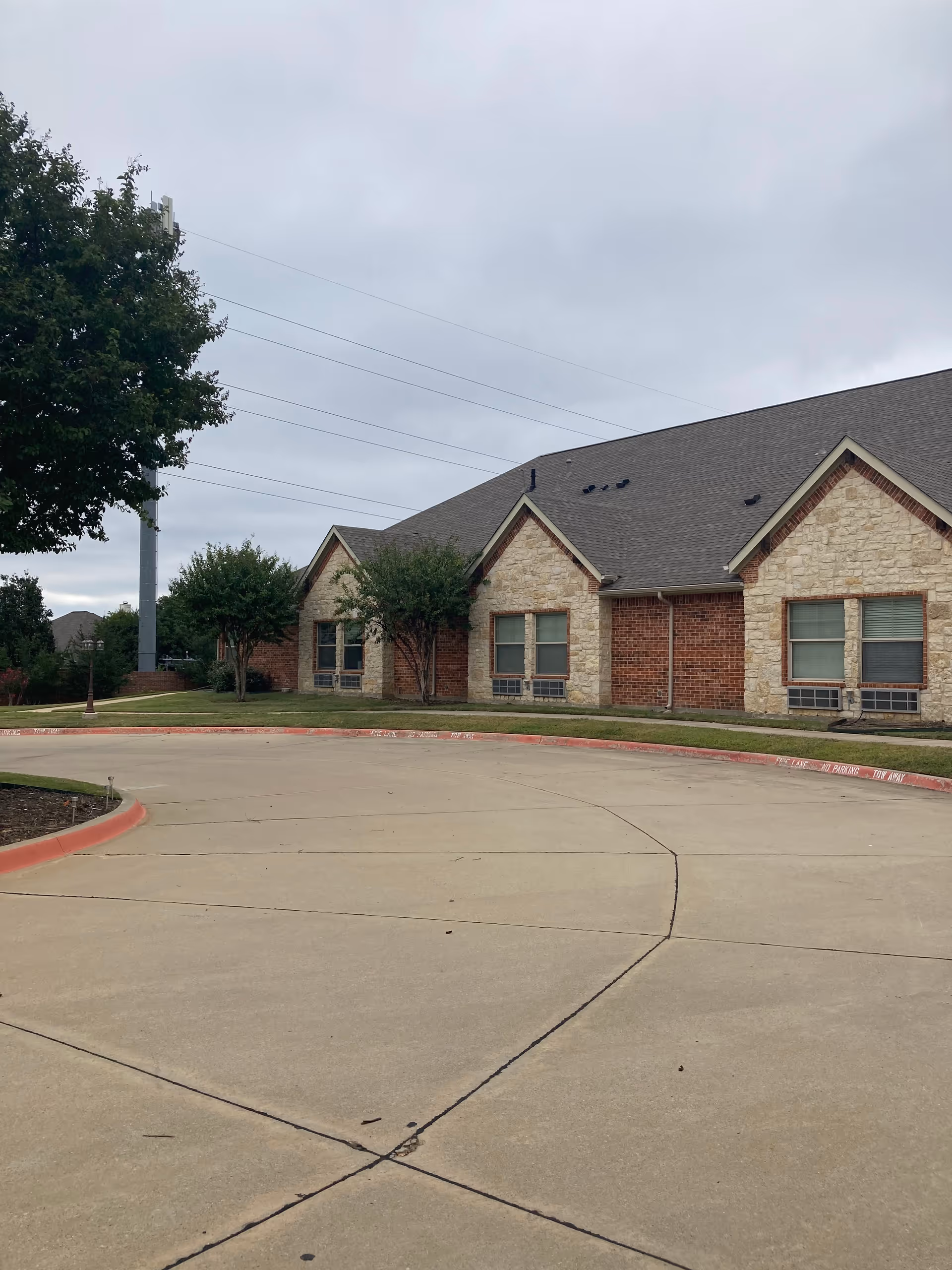 Single-story brick and stone senior living facility with curved driveway and manicured lawn.