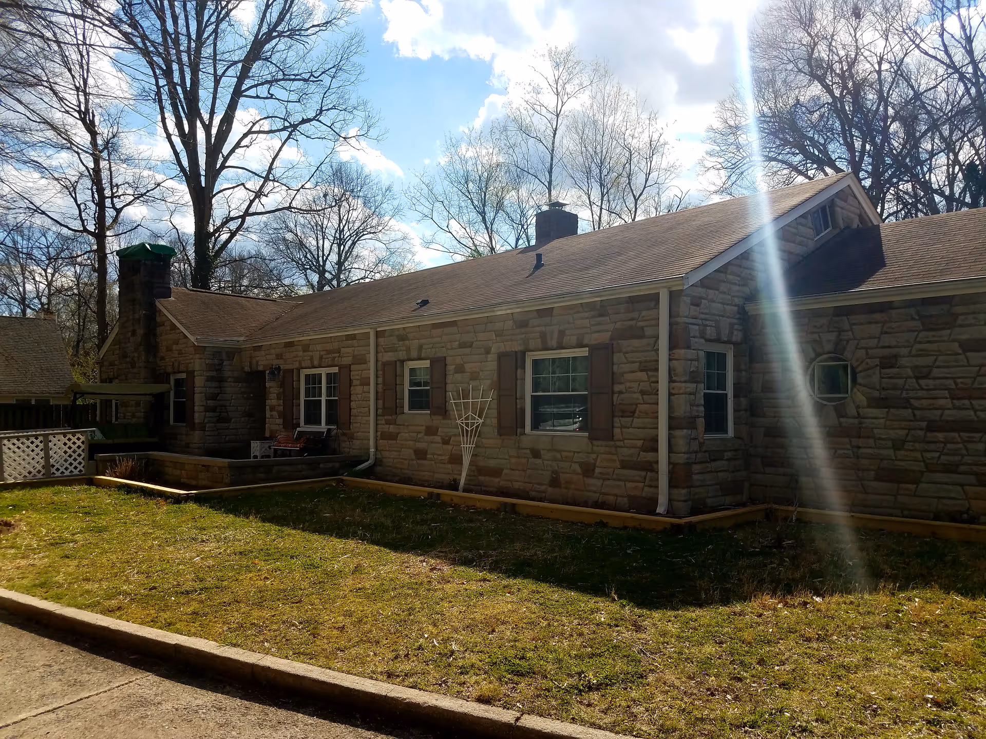 Exterior view of a single-story stone senior living facility with lawn and leafless trees.