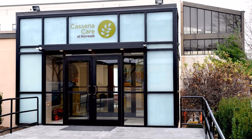 Glass-front entrance of Cassena Care at Norwalk with double doors and frosted glass panels.