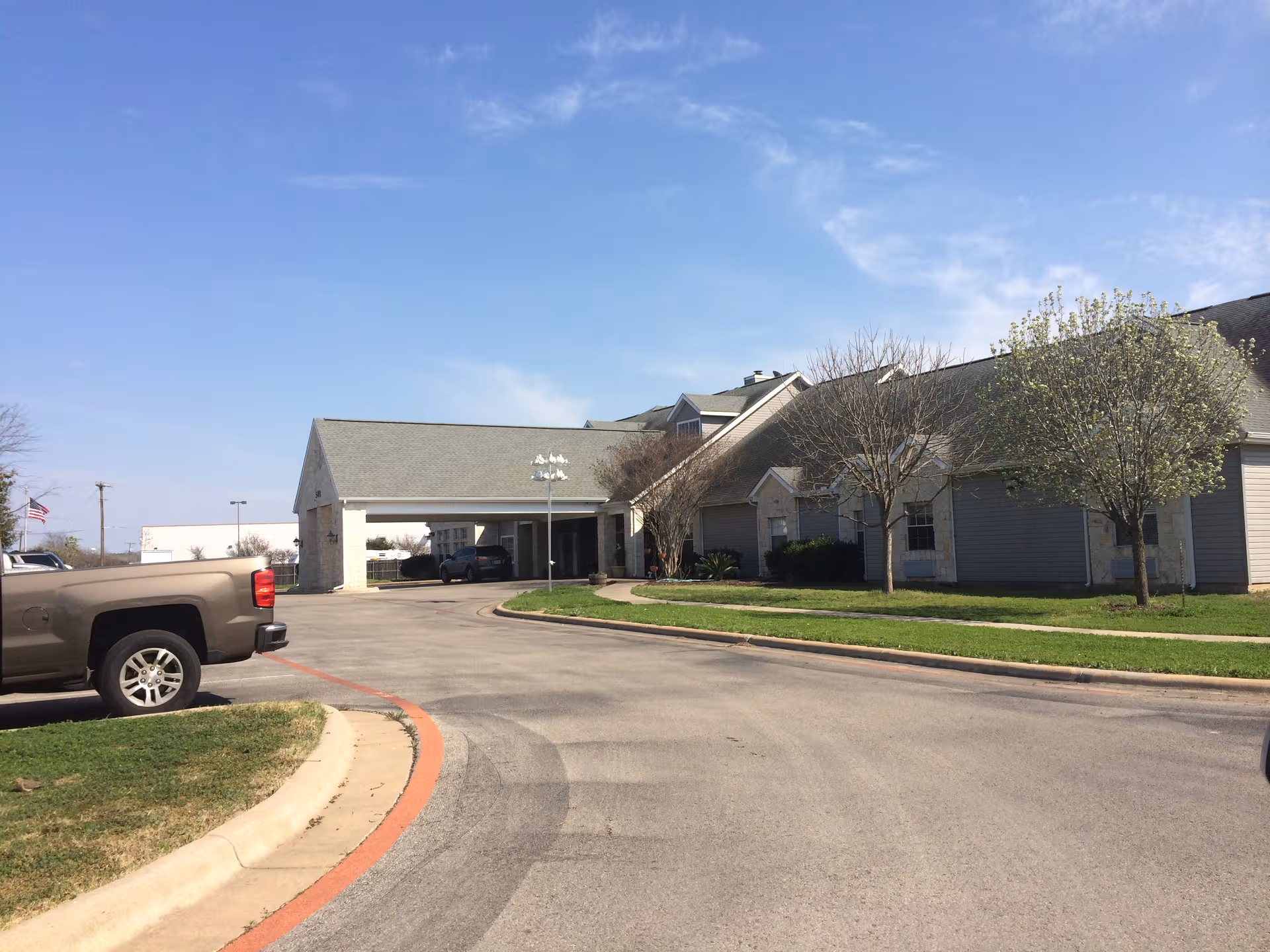 Exterior view of Argent Court Assisted Living with driveway, entrance and parked cars.
