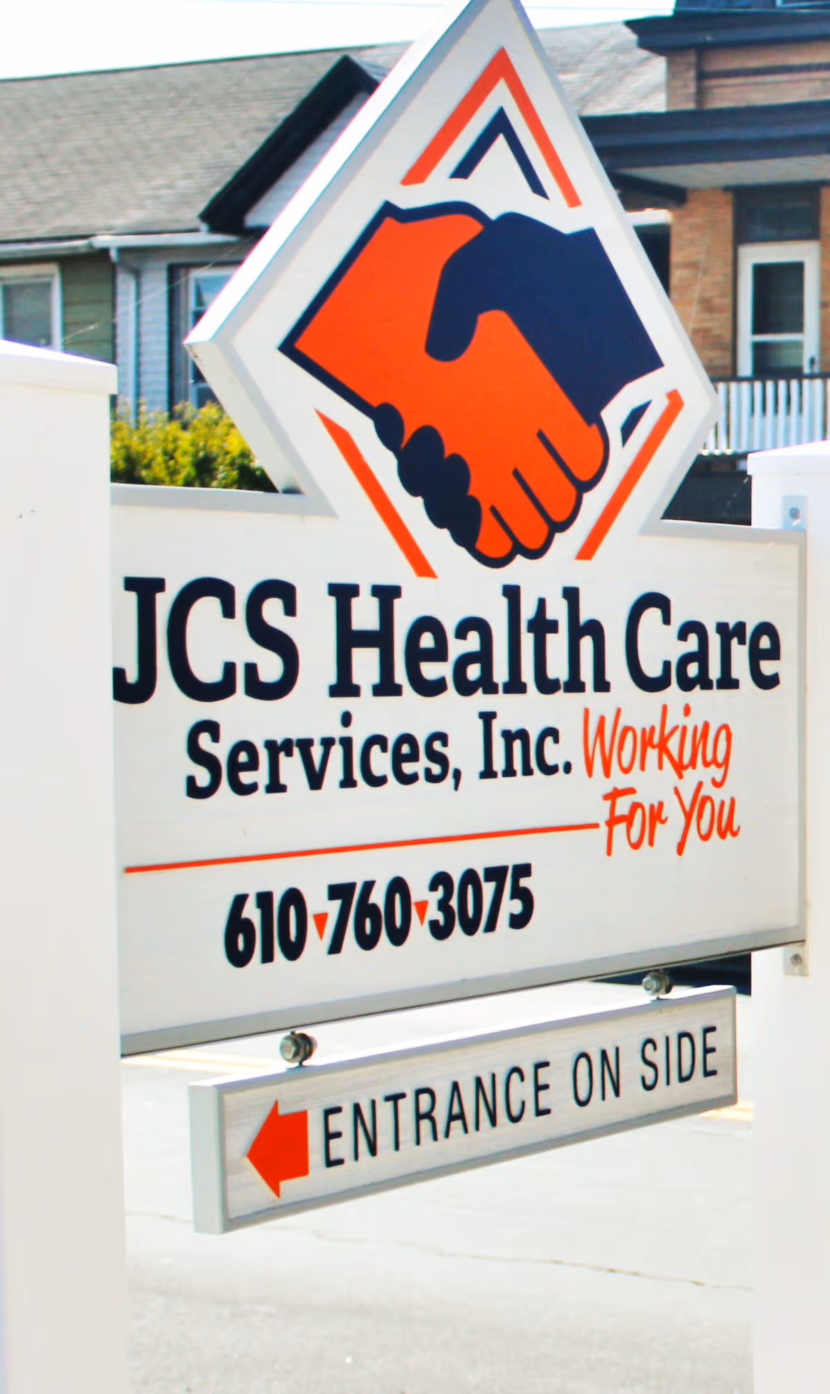 Exterior sign for JCS Health Care Services with handshake logo and entrance arrow