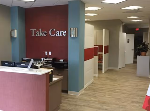 Reception area with Take Care sign, hallway to private rooms and a front desk.