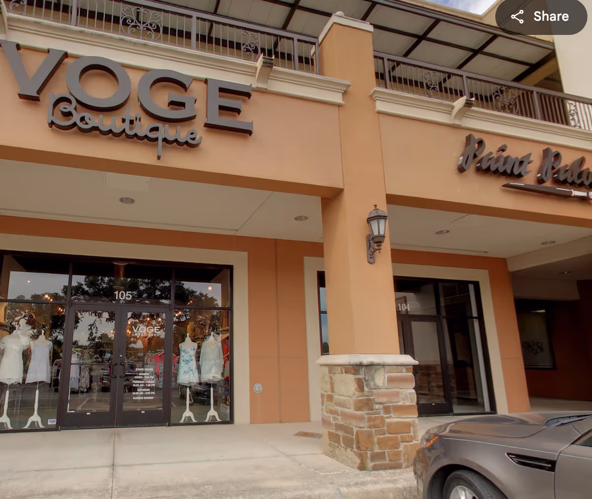 Exterior storefront with VOGE Boutique signage and a parked car.