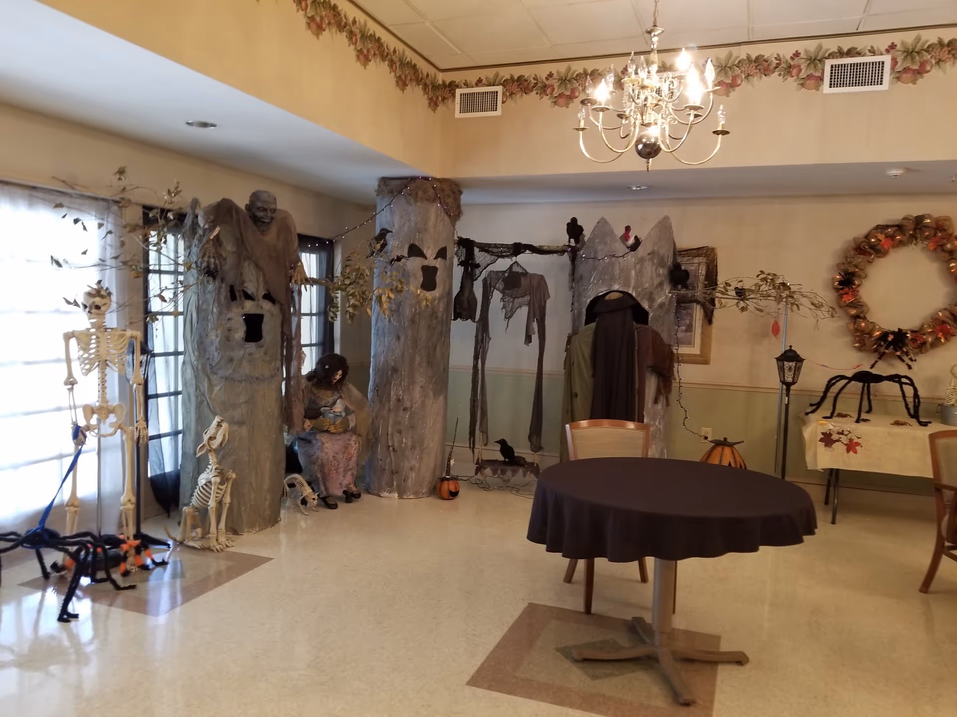 Interior common area with Halloween decorations, skeleton props, and a round table.