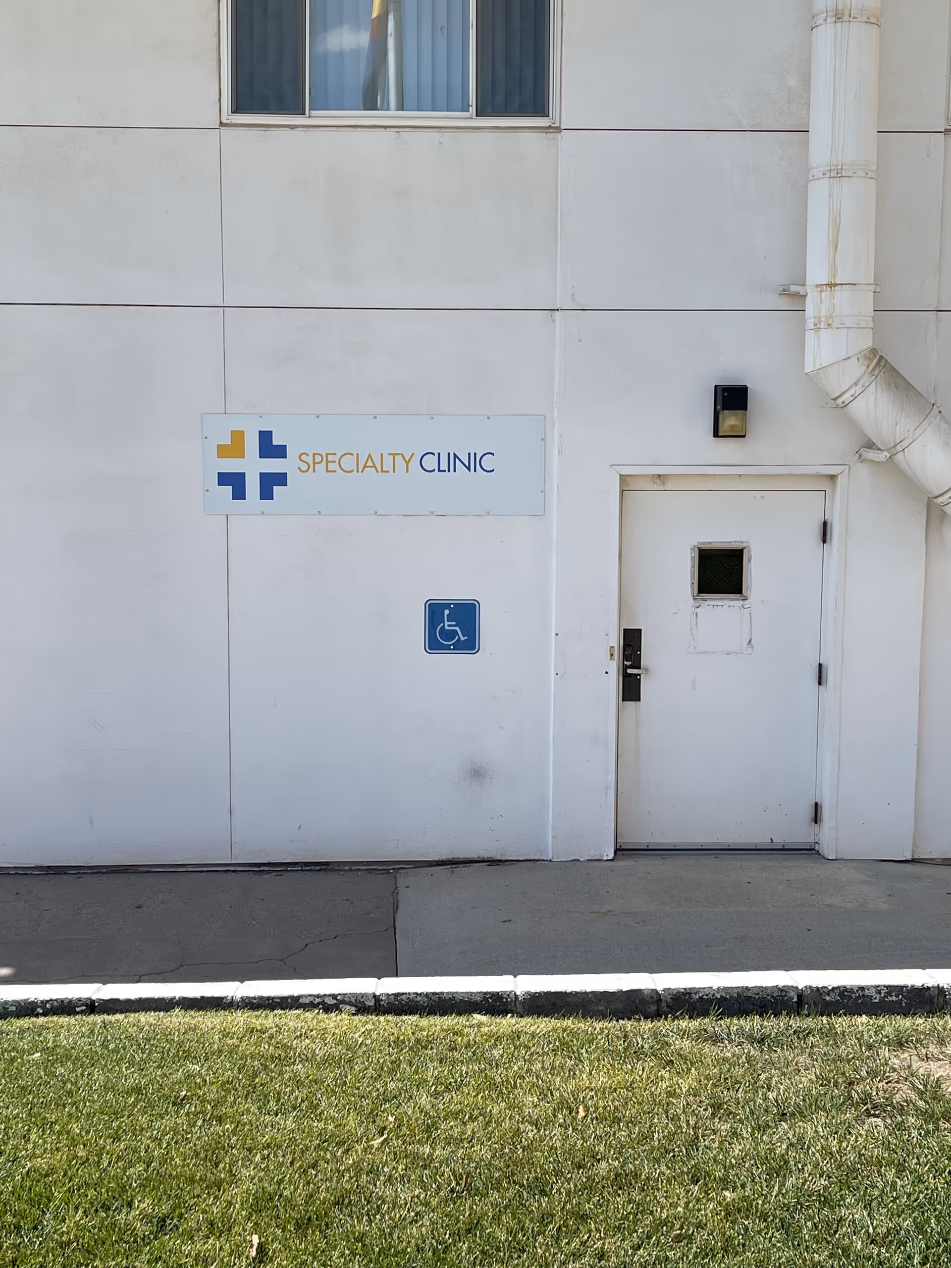 White building exterior with a clinic sign and wheelchair-accessible icon near a door