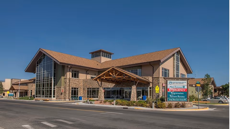Exterior view of West Park Hospital senior living facility with glass entrance and stone accents.