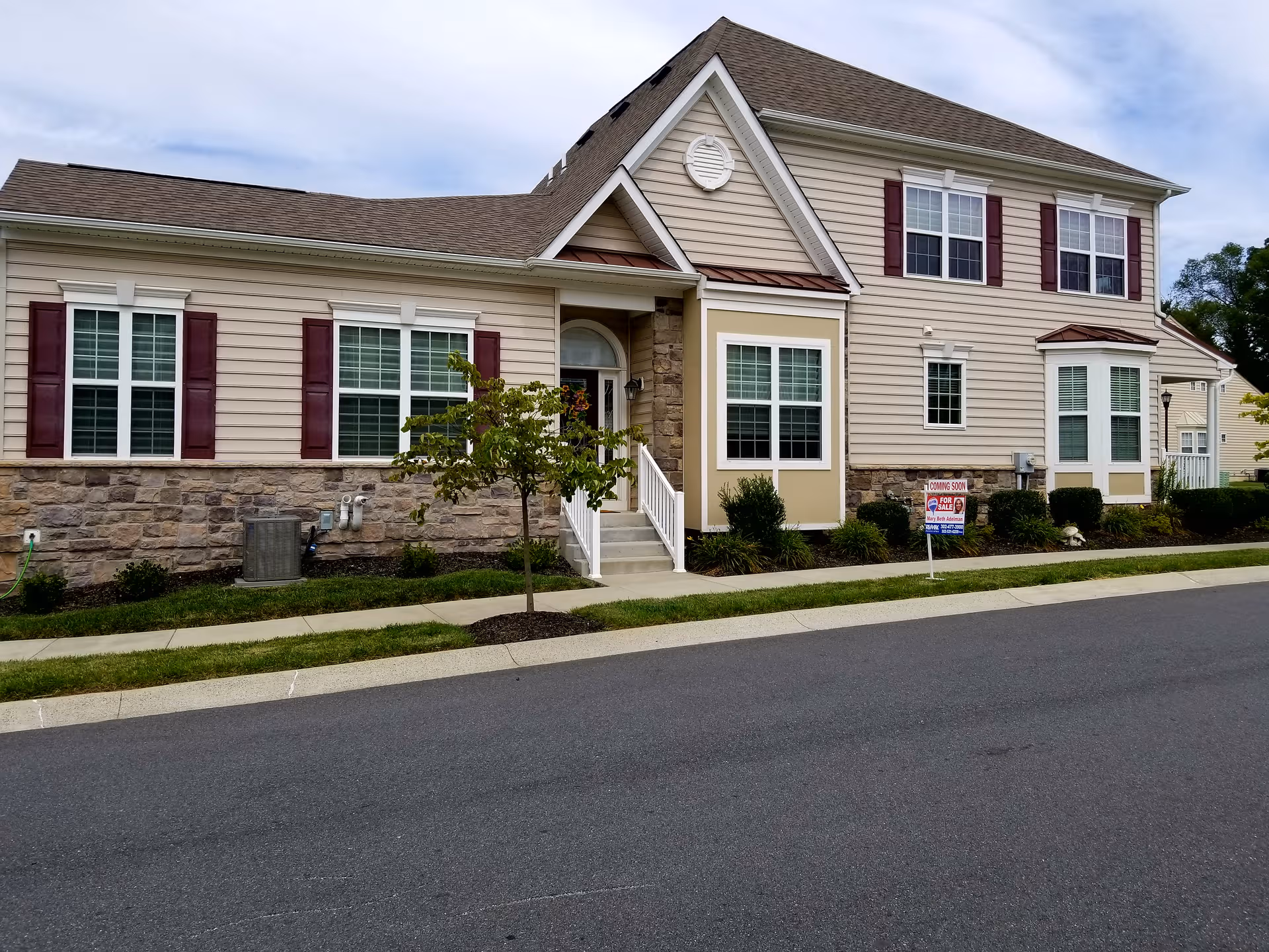 Exterior view of Village of Brandywine's beige, two-story building with stone base and landscaping.