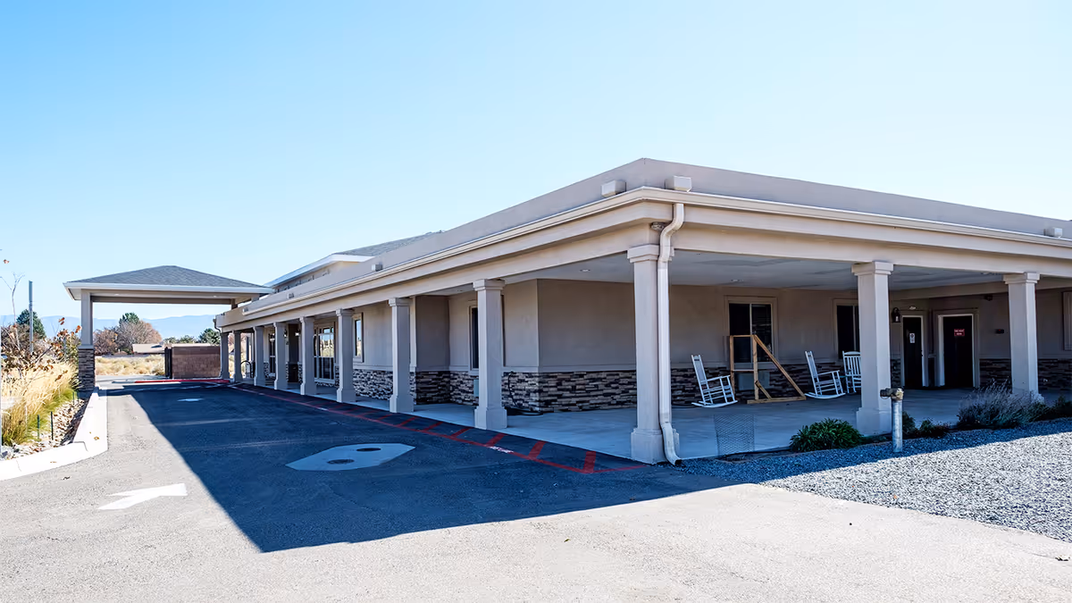 Exterior view of Bee Hive Homes of Volcano Cliffs featuring a covered entrance and rocking chairs.