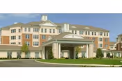 A large, multi-story senior living facility with a covered entrance and manicured landscaping.