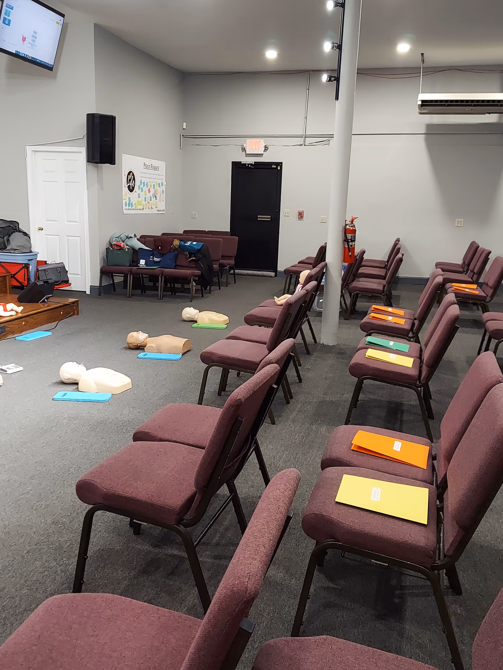 Rows of purple chairs arranged for CPR training, with manikins on the floor.