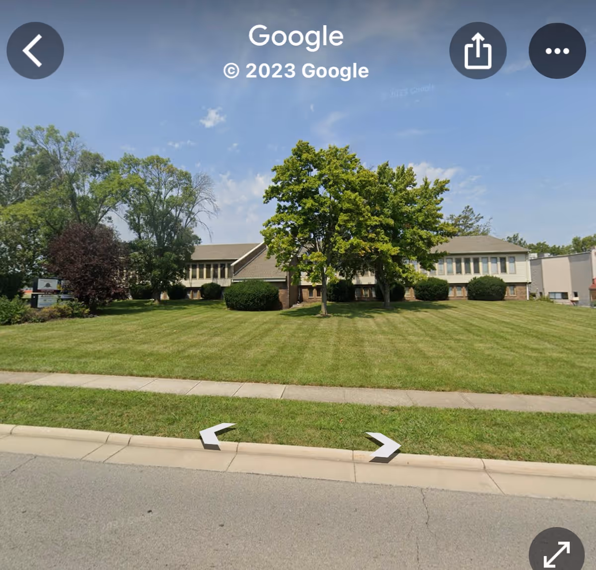 Front view of a senior living facility with a manicured lawn and trees.