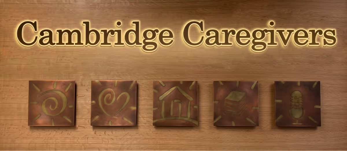 Wooden wall with Cambridge Caregivers sign and five decorative tiles.