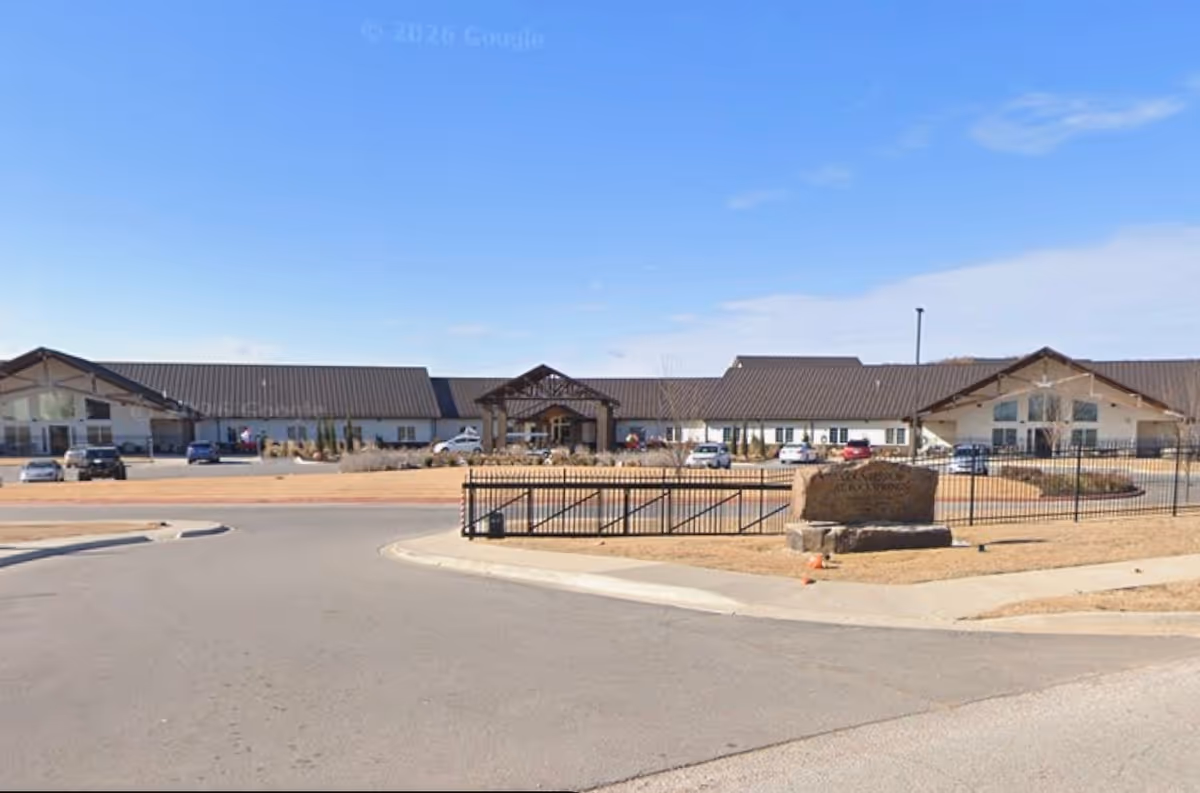 Front view of a single-story senior living facility with a gated entrance.