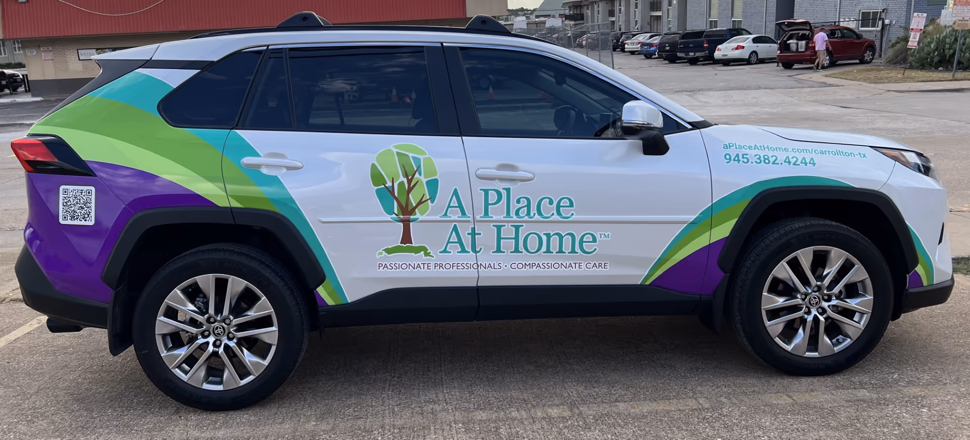 Colorful promotional SUV with A Place At Home Carrollton logo parked in a lot