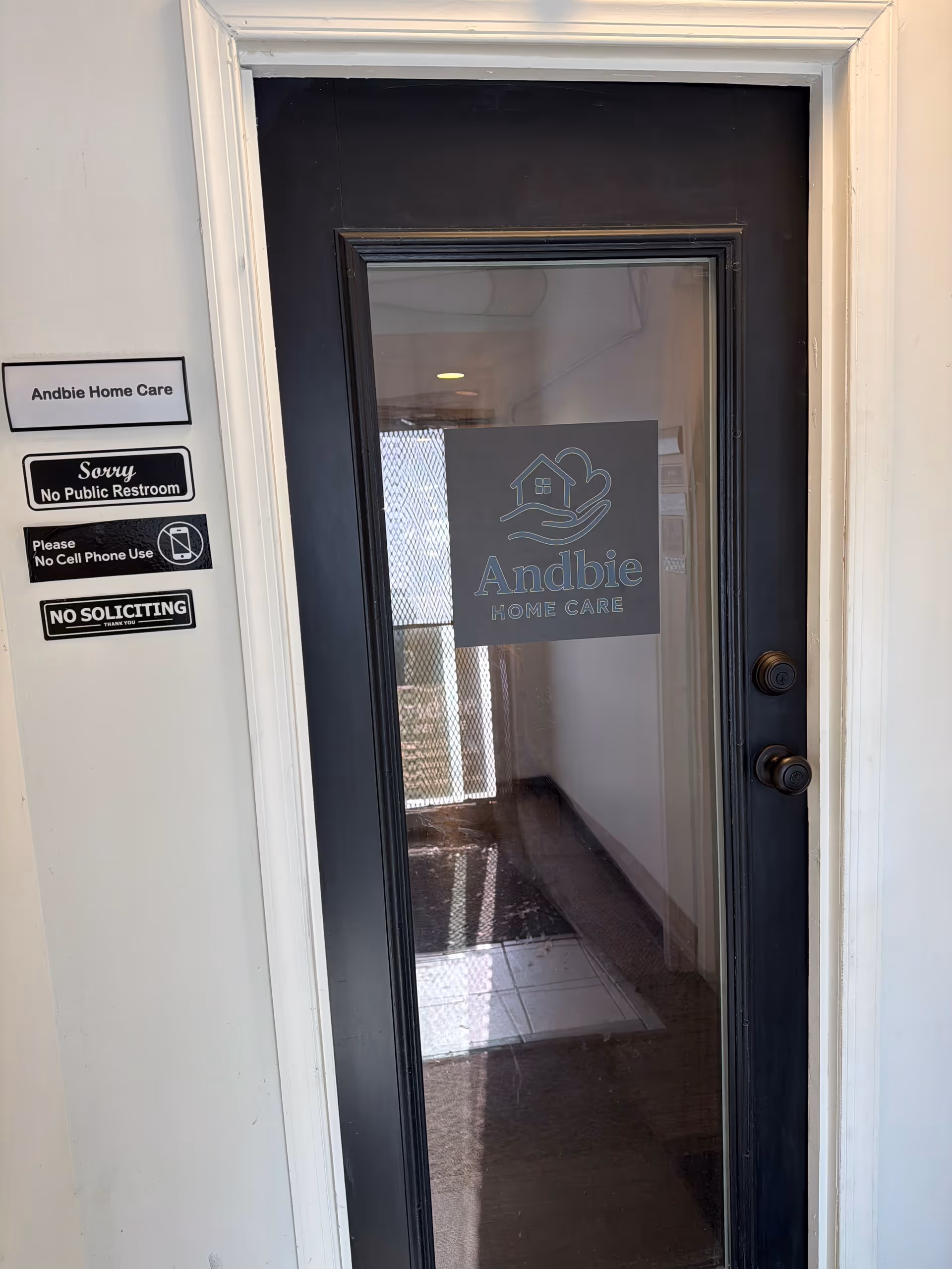 Glass entrance door with Andbie Home Care sign and wall notices on left